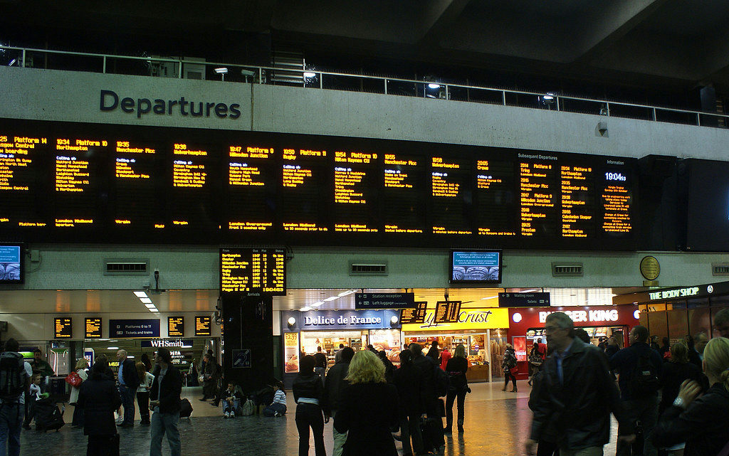 Travelers at an airport terminal during peak travel hours with departure boards visible