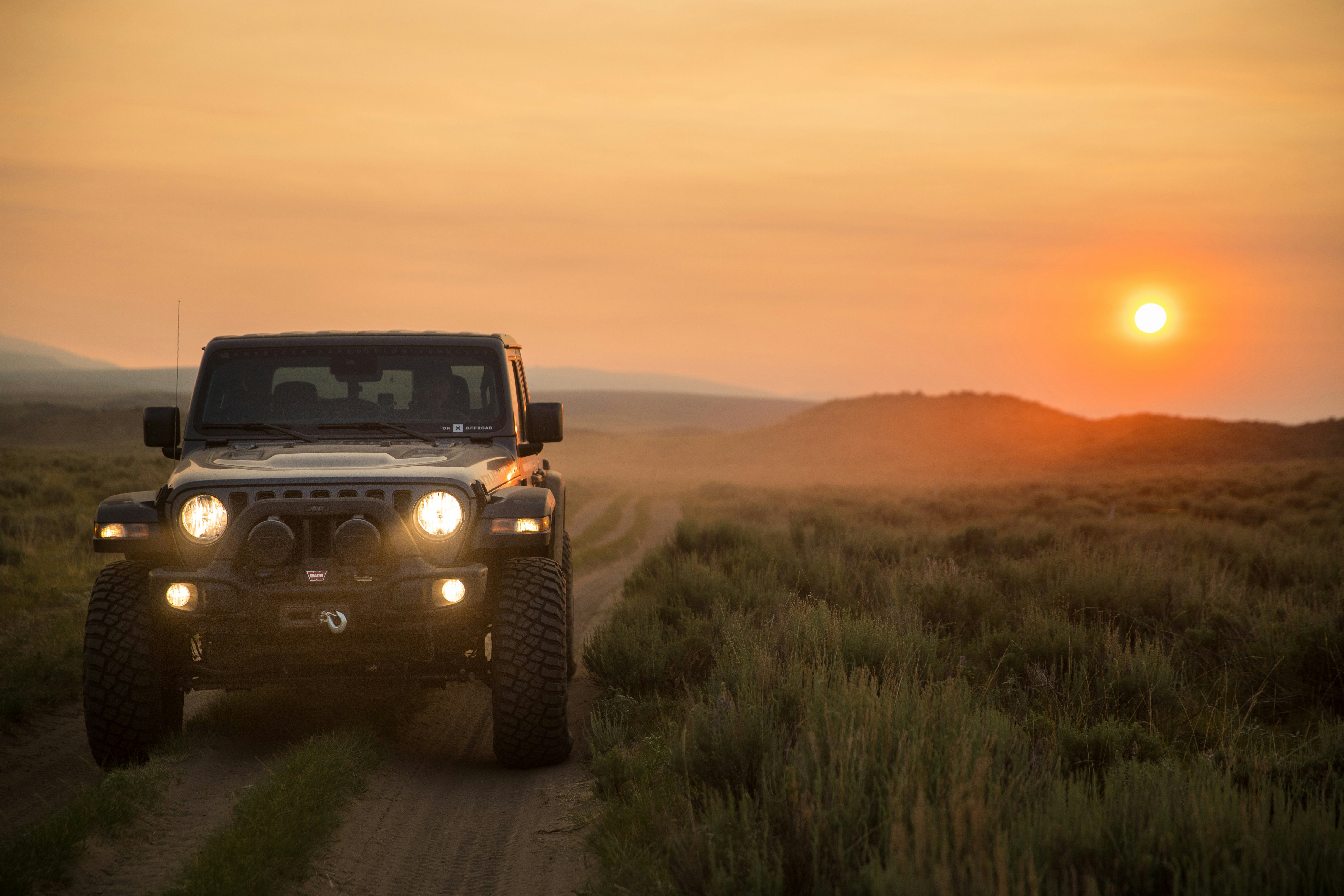 Safari-Jeep mit Touristen und Sonnenuntergang im Hintergrund