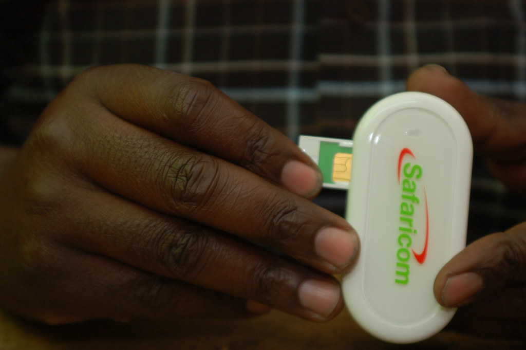Smartphone, physical SIM card and passport arranged for mobile connectivity while travelling in Kenya